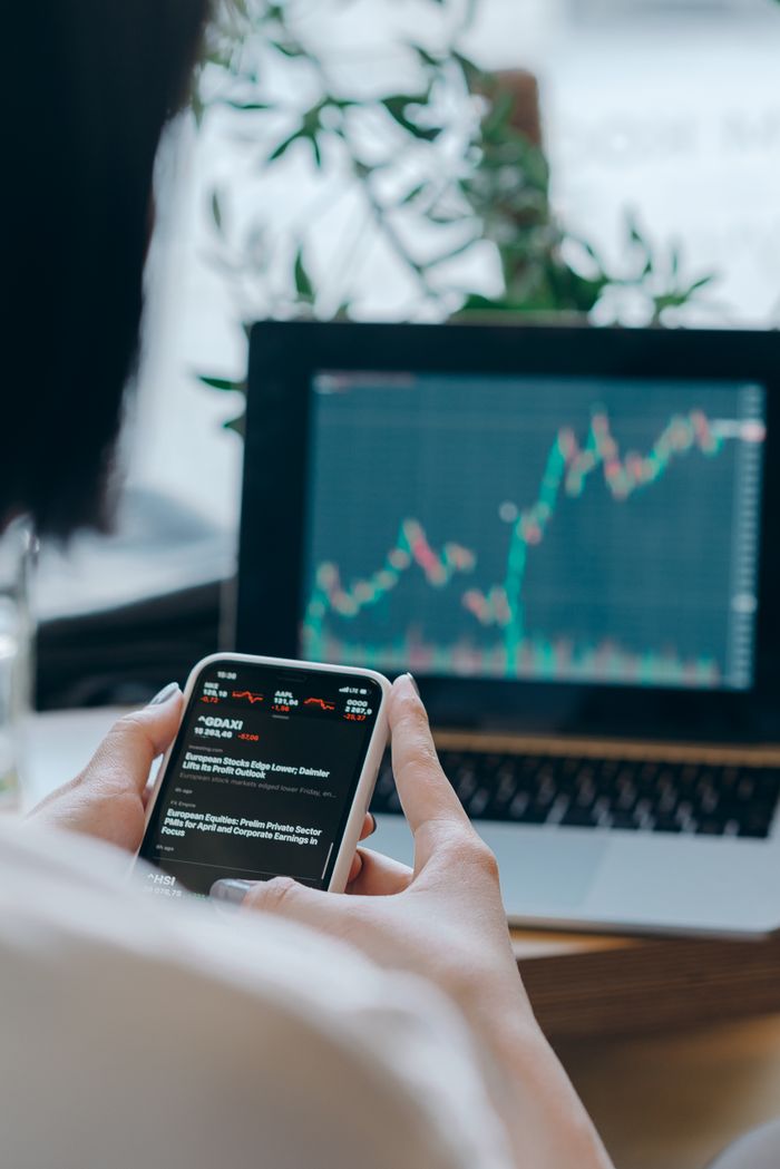 services-02 Person using smartphone for stock market analysis at home office.
